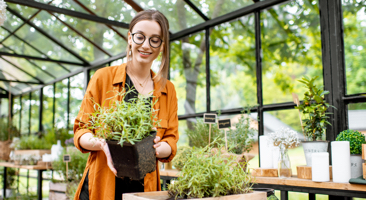 Image of a gardener tending to her plant in a green house