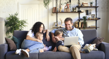 family sitting on a sofa looking at a laptop
