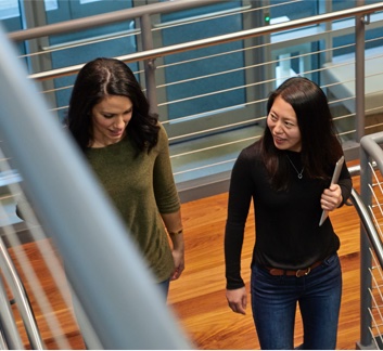 Two Constant Contact employees talking while they walk down the stairs.