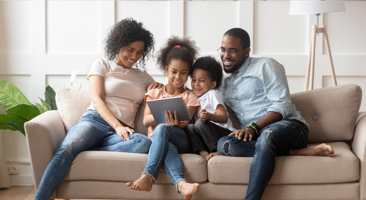 family on a sofa looking at a tablet device