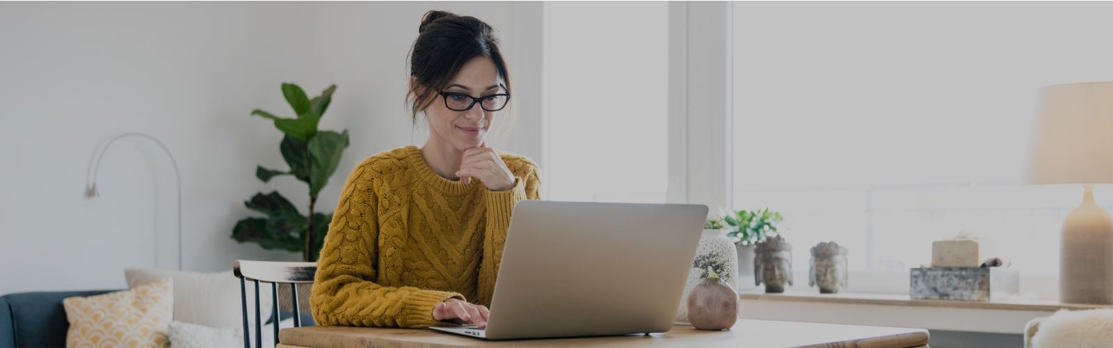 woman in a yellow sweater sitting at a laptop