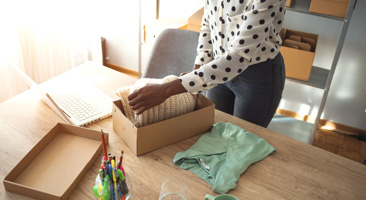 person packing a gift box with clothes