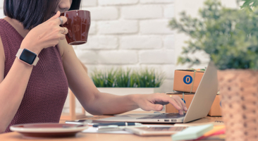 Image of a woman drinking coffee while working on her computer