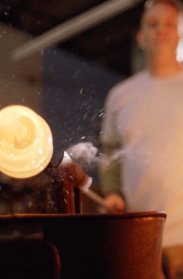 Person demonstrates glass blowing.