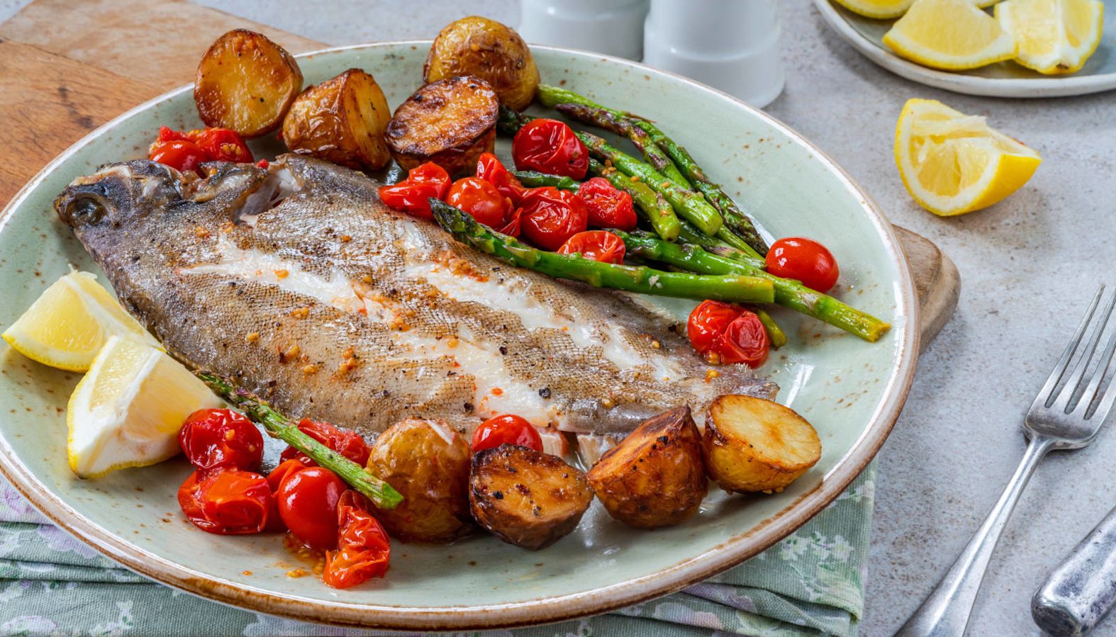 Lemon sole with tomatoes, potatoes and asparagus on a plate - wine with fish