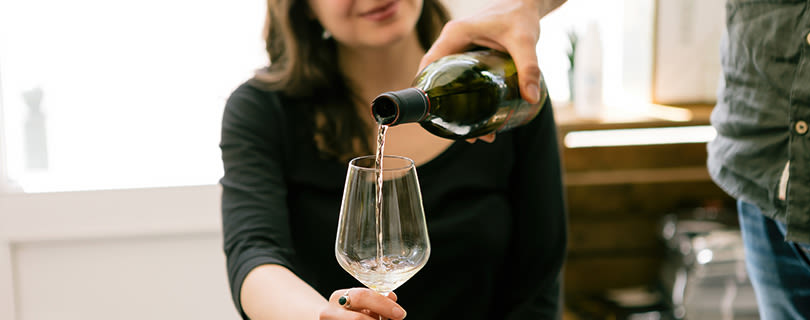 A man pouring white wine into his girlfriend's wine glass - Italian white wine