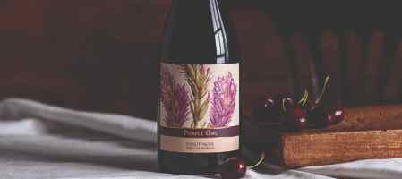 Bottle of Purple Owl Pinot Noir on a table with a white cloth