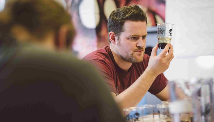Man holding up sample of beer for inspection at a beer tasting