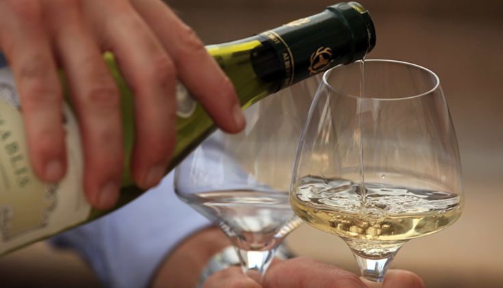 Bottle of Chablis being poured into one of two glasses