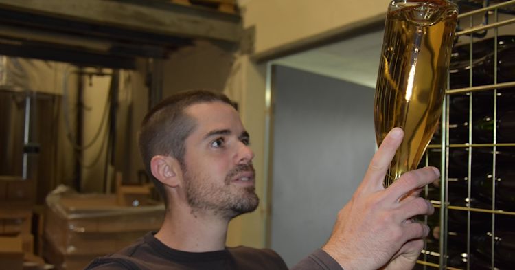 A man holding a Champagne bottle upside down looking at its colour.