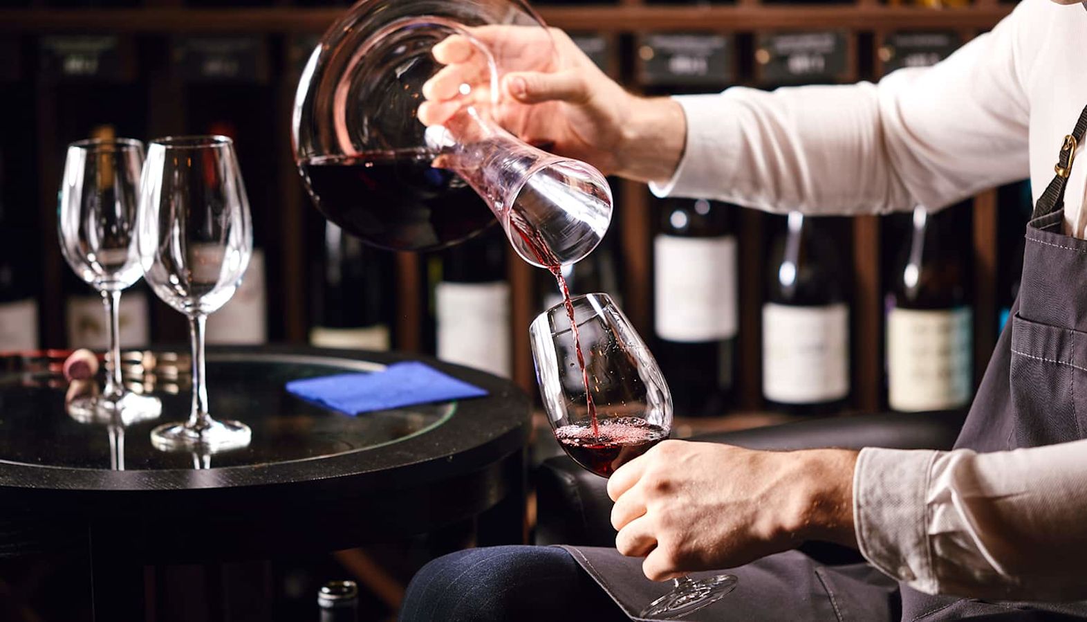 A sommelier decanting a bottle of red wine at a wine tasting event - decanting a wine