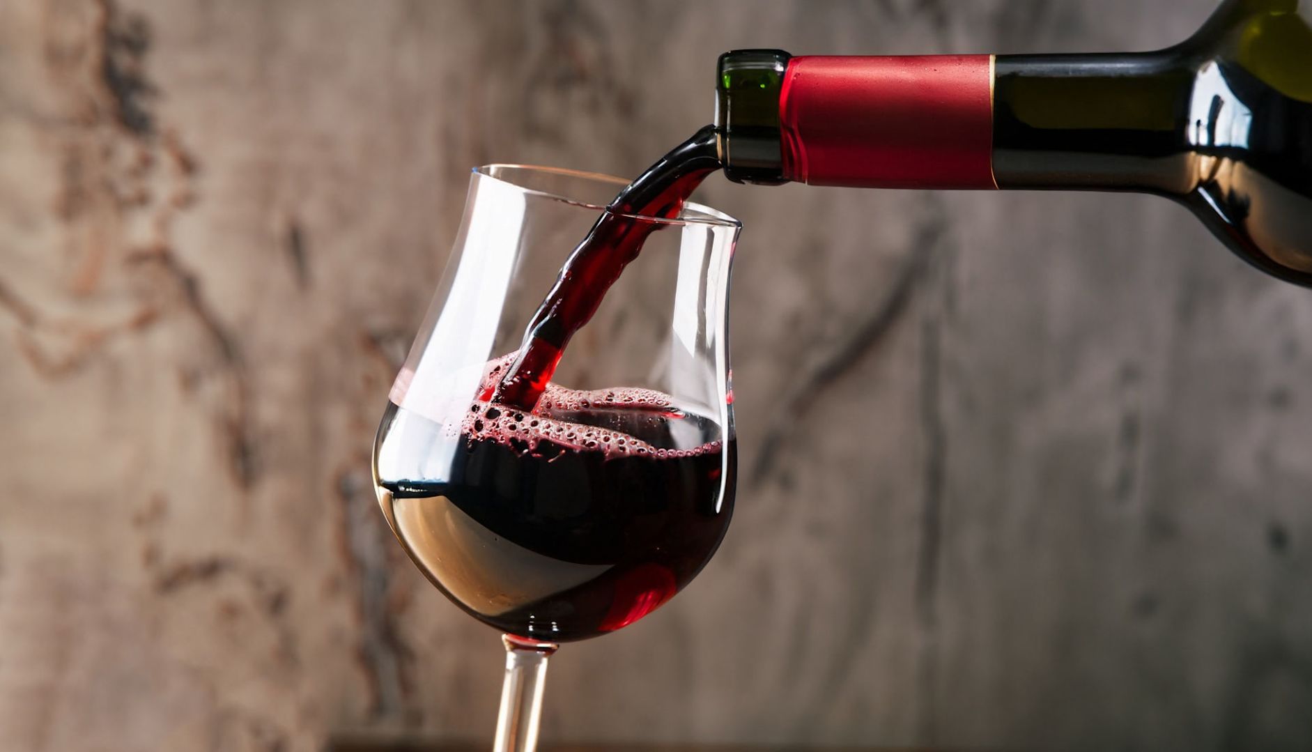 An introductory guide to French Bordeaux wines - a glass of red Bordeaux wine being poured into a glass from a bottle.