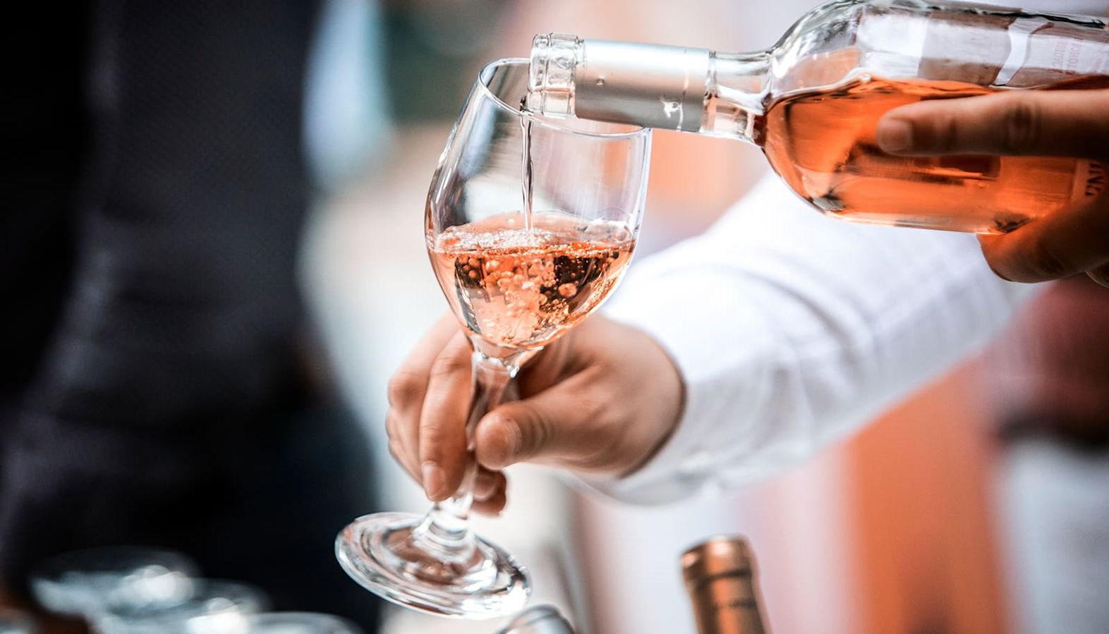 Sparkling rose wine being poured into a glass - decanting a wine