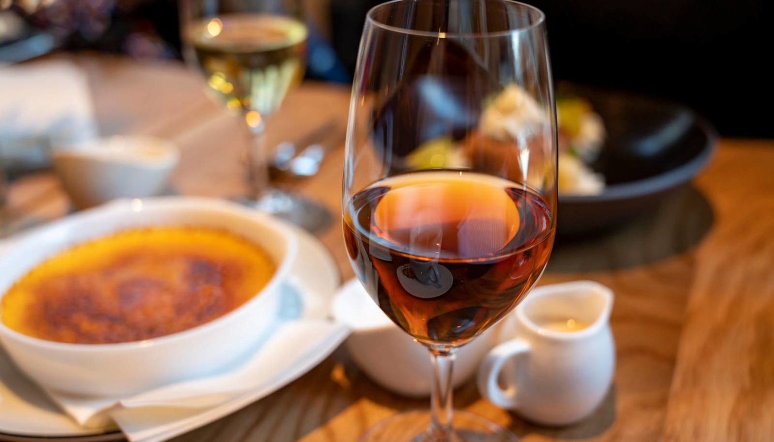 A glass of Sherry with a creme brulee dessert at a restaurant - Sherry wine