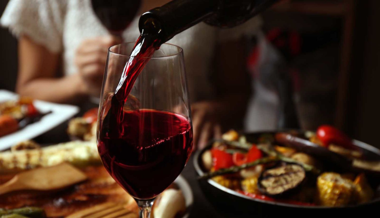 Vegan wine - a glass of red wine is poured at a dining table