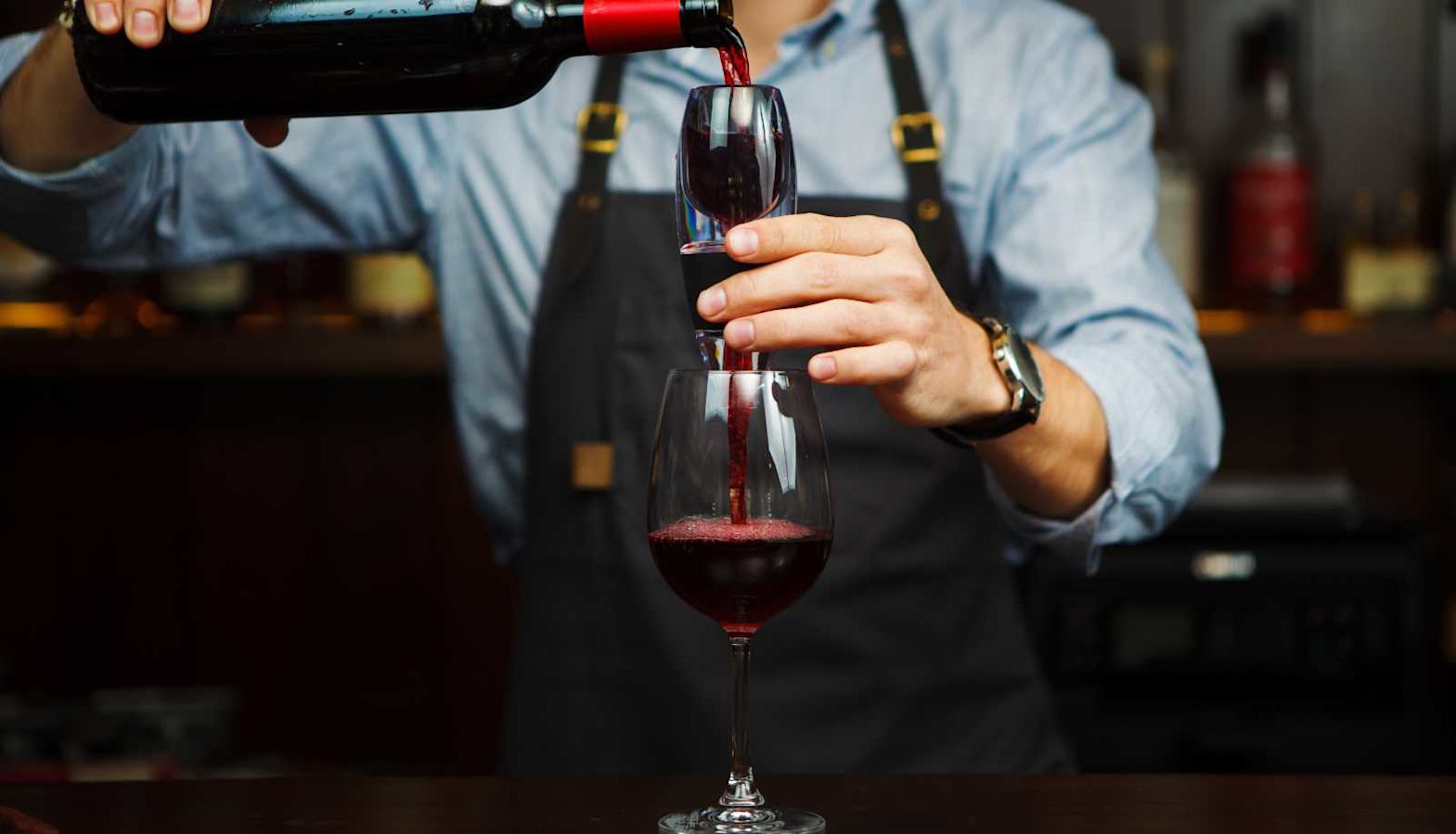 Wine aeration - a man pours red wine through an aerator