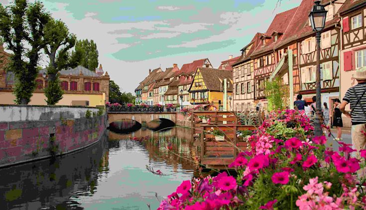 A canal in Alsace with picturesque timbered buildings and flowers in the foreground
