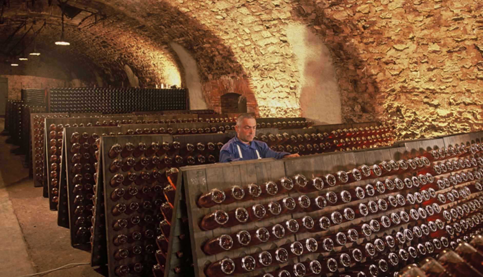 winemaker in wine cellar filled with bottles