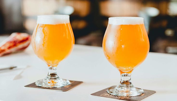 Two glasses of hazy IPA on a table with a blurred background