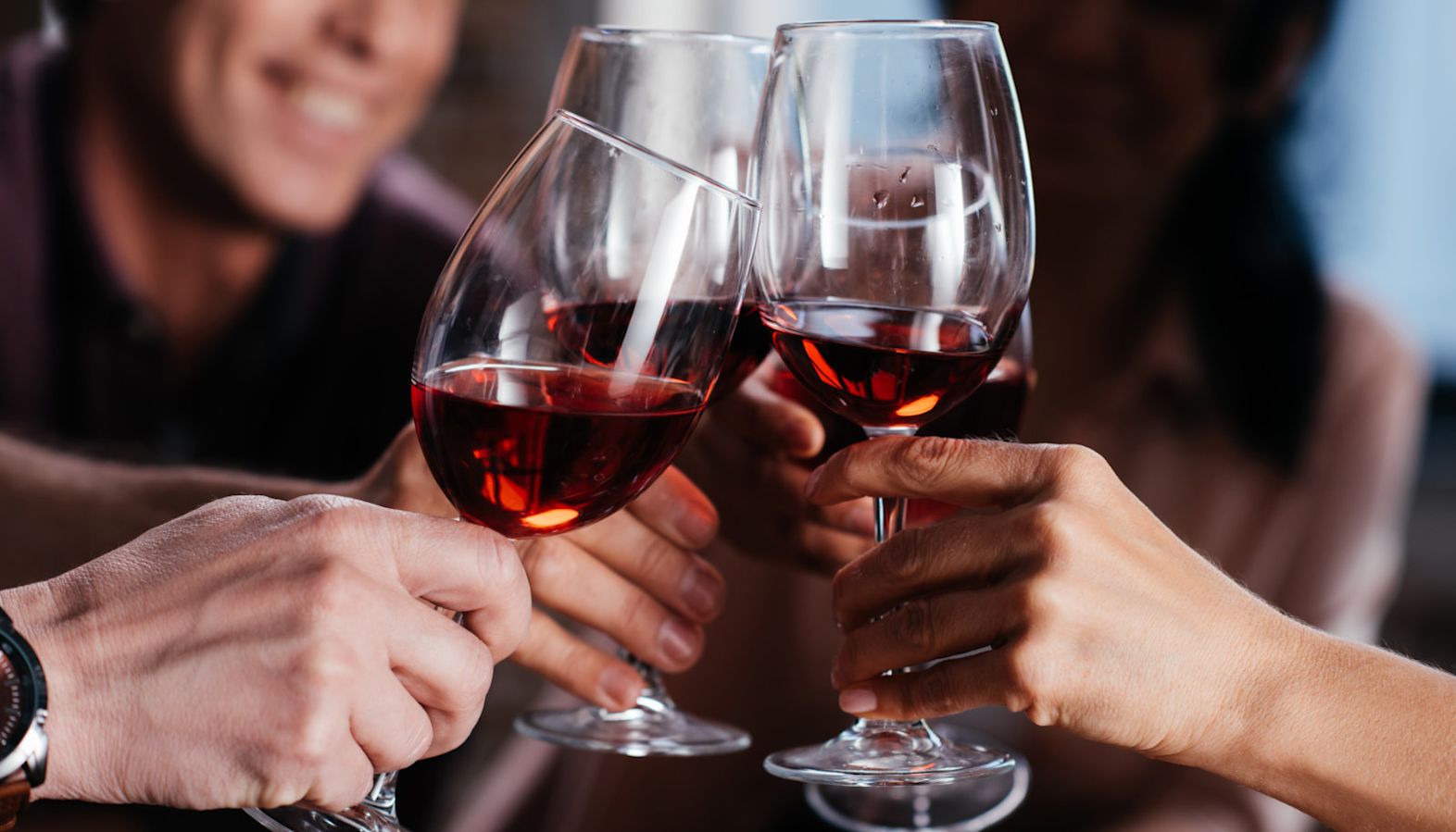 A group of friends raising glasses of red wine in celebration - wine ratings