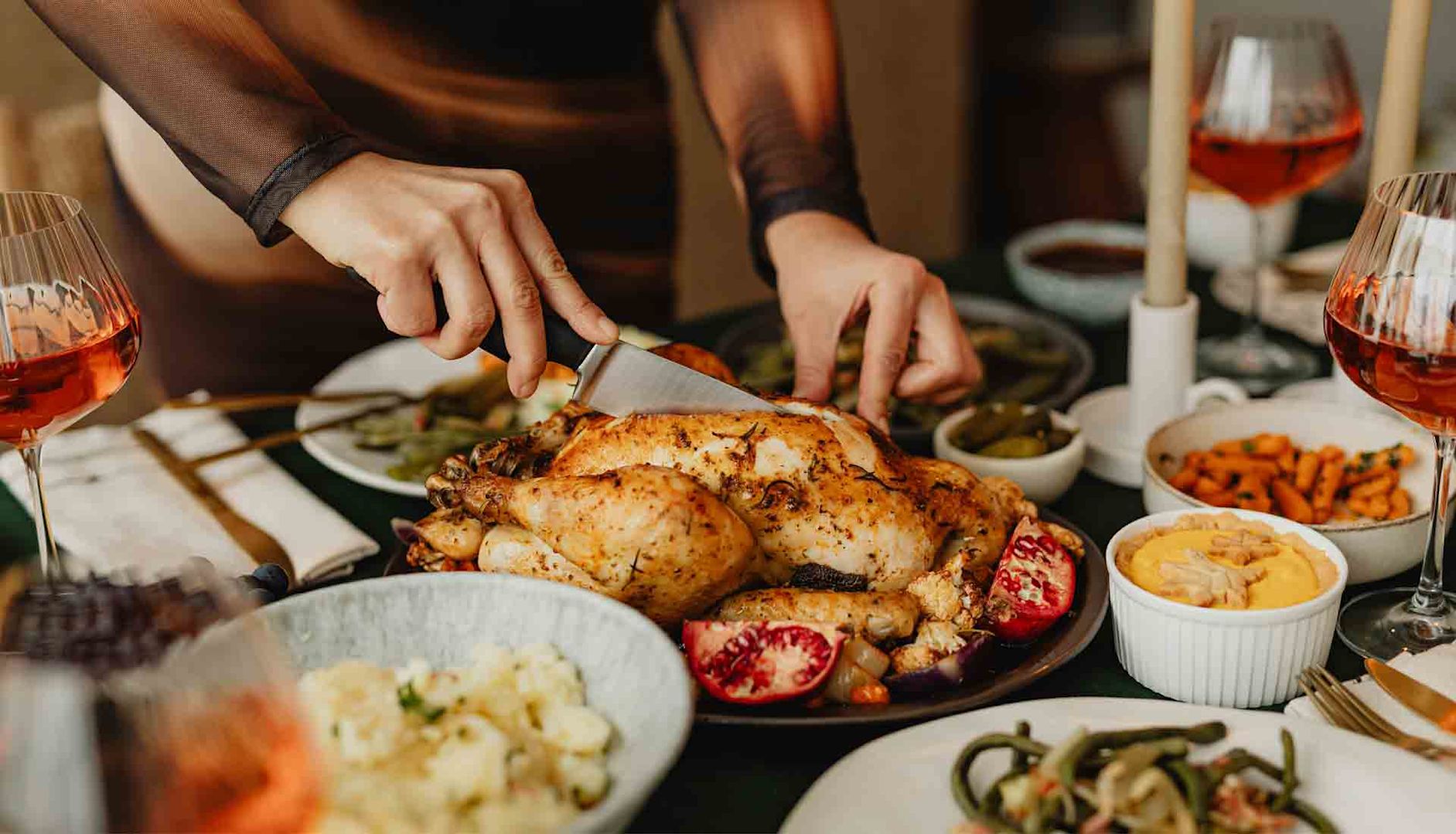 A man cutting chicken for an easter feast with red wine in background