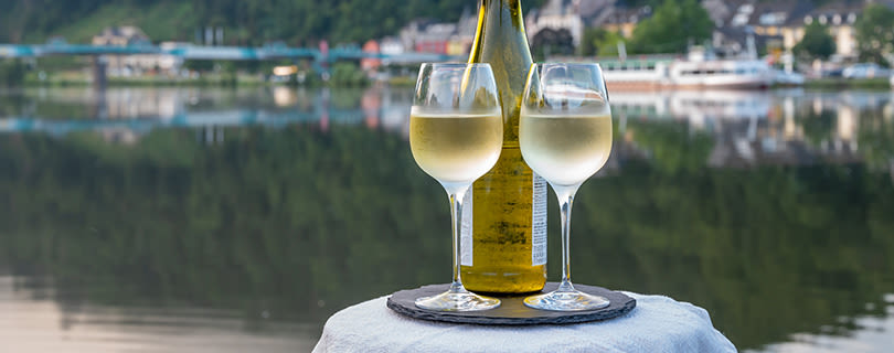 A bottle of Riesling wine and two glasses overlooking a scenic lake - German white wine