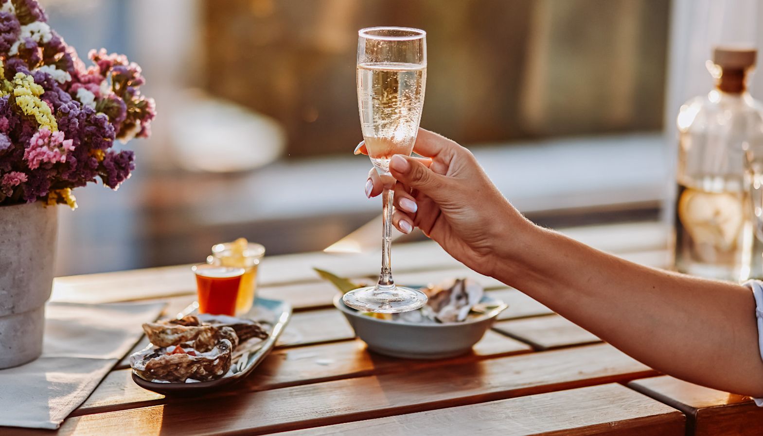 A person enjoying a glass of sparkling wine at a picnic table - English sparkling wine