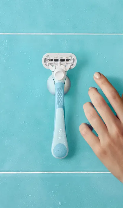 Eine weibliche Hand greift nach dem nachfüllbaren Gillette Venus Extra Smooth Rasierer am Duschhalter