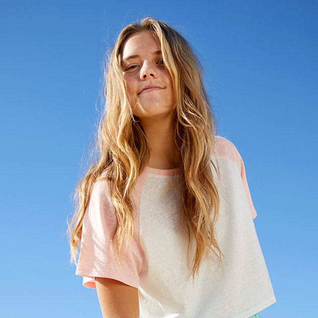 Teenager-Mädchen lächelnd unter einem klaren Himmel