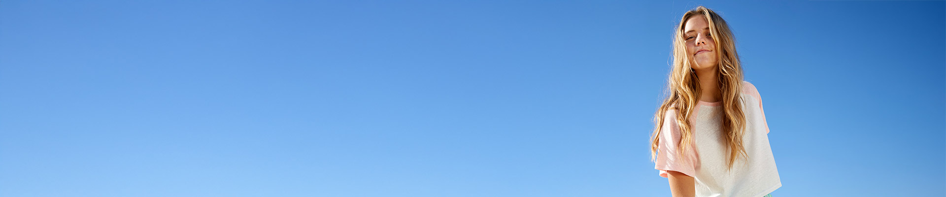 Teenager-Mädchen lächelnd unter einem klaren Himmel
