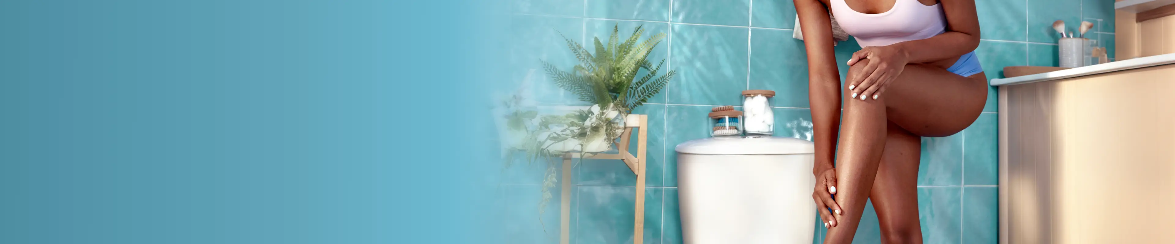 Une femme est assise dans une baignoire et se rase la jambe avec un rasoir Gillette Venus, entourée d'une salle de bains carrelée et lumineuse.