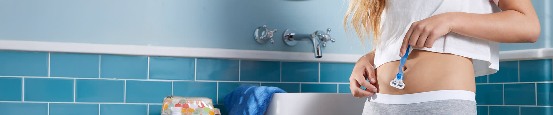 Junge Dame rasiert sich im Badezimmer den Bauch