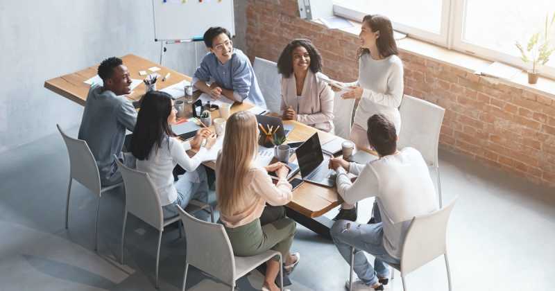 Eine bunt gemischte Gruppe von Kollegen diskutiert an einem Tisch in einem modernen Büro.