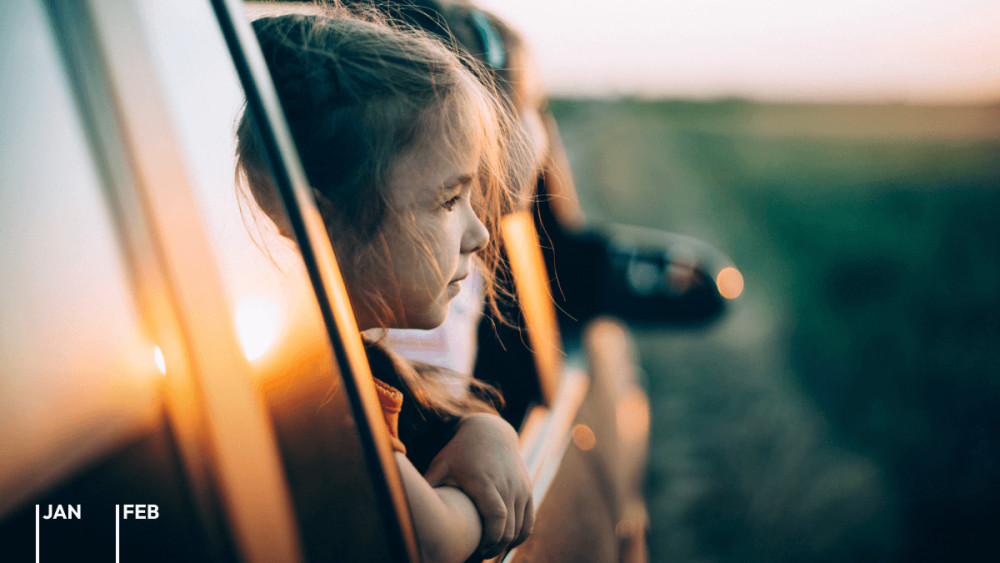 Zwei Mädchen schauen aus den Seitenfenstern eines fahrenden Autos im Sonnenuntergang