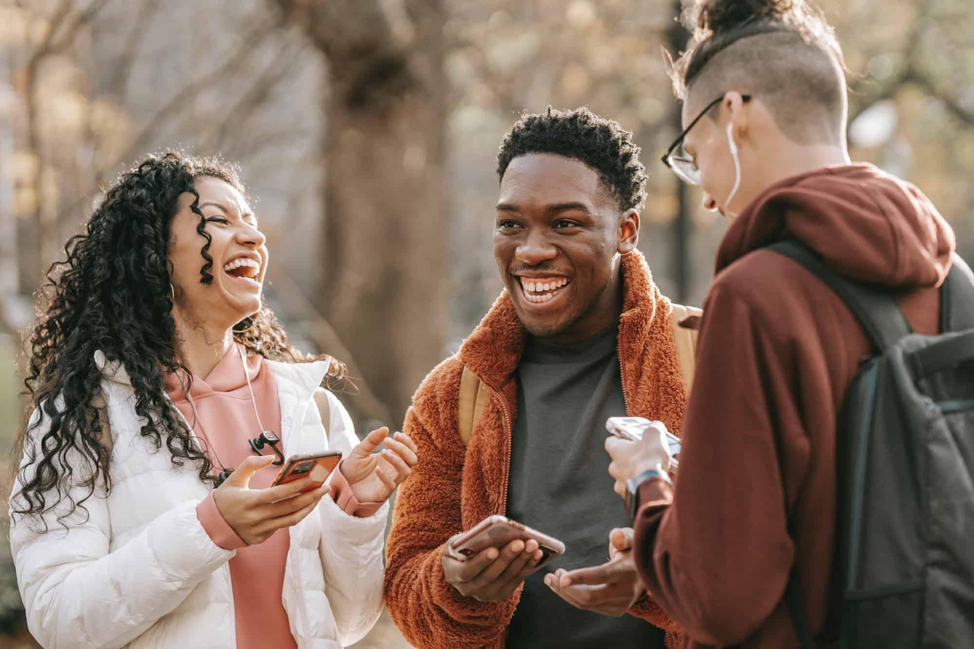 Skrattande vänner från olika bakgrund med smartphone