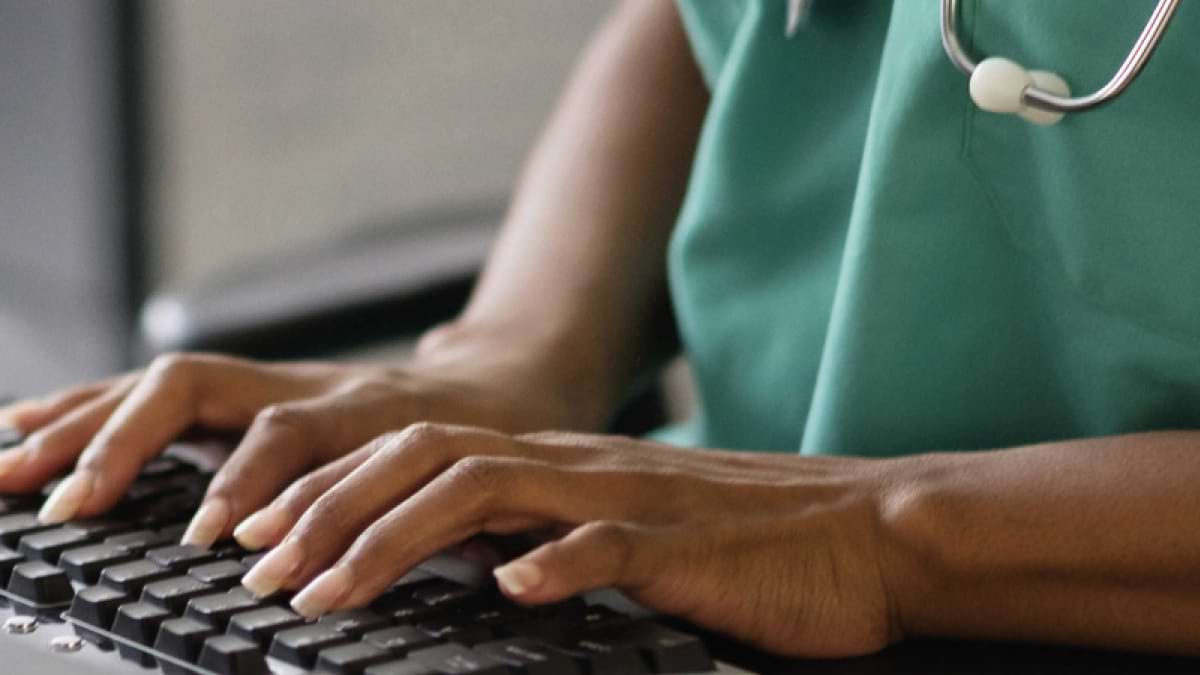 A healthcare professional's hands typing on a keyboard. 