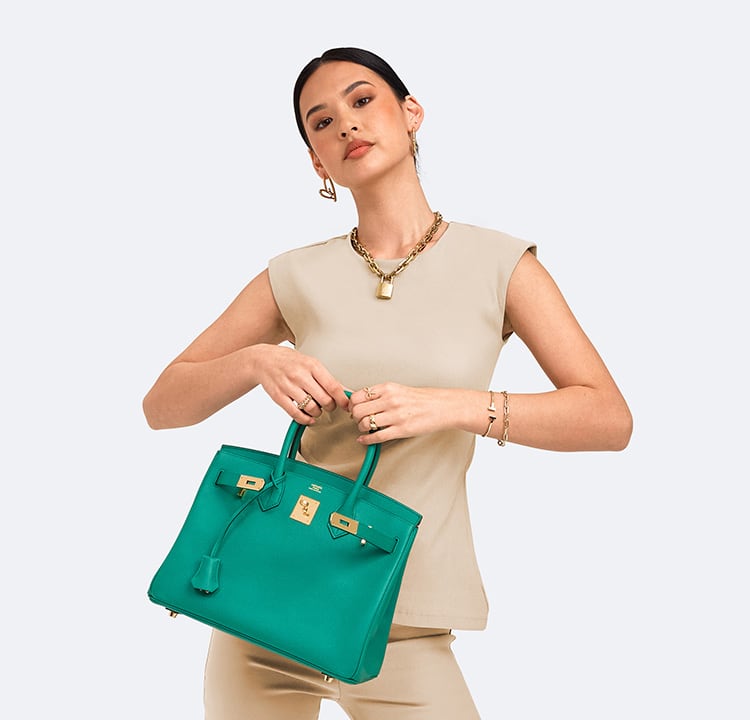 a woman in a beige top and pants holding a green Hermes Birkin