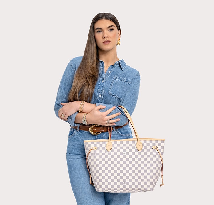 a woman in a denim button down and pants holding a Louis Vuitton Damier Azur Neverfull