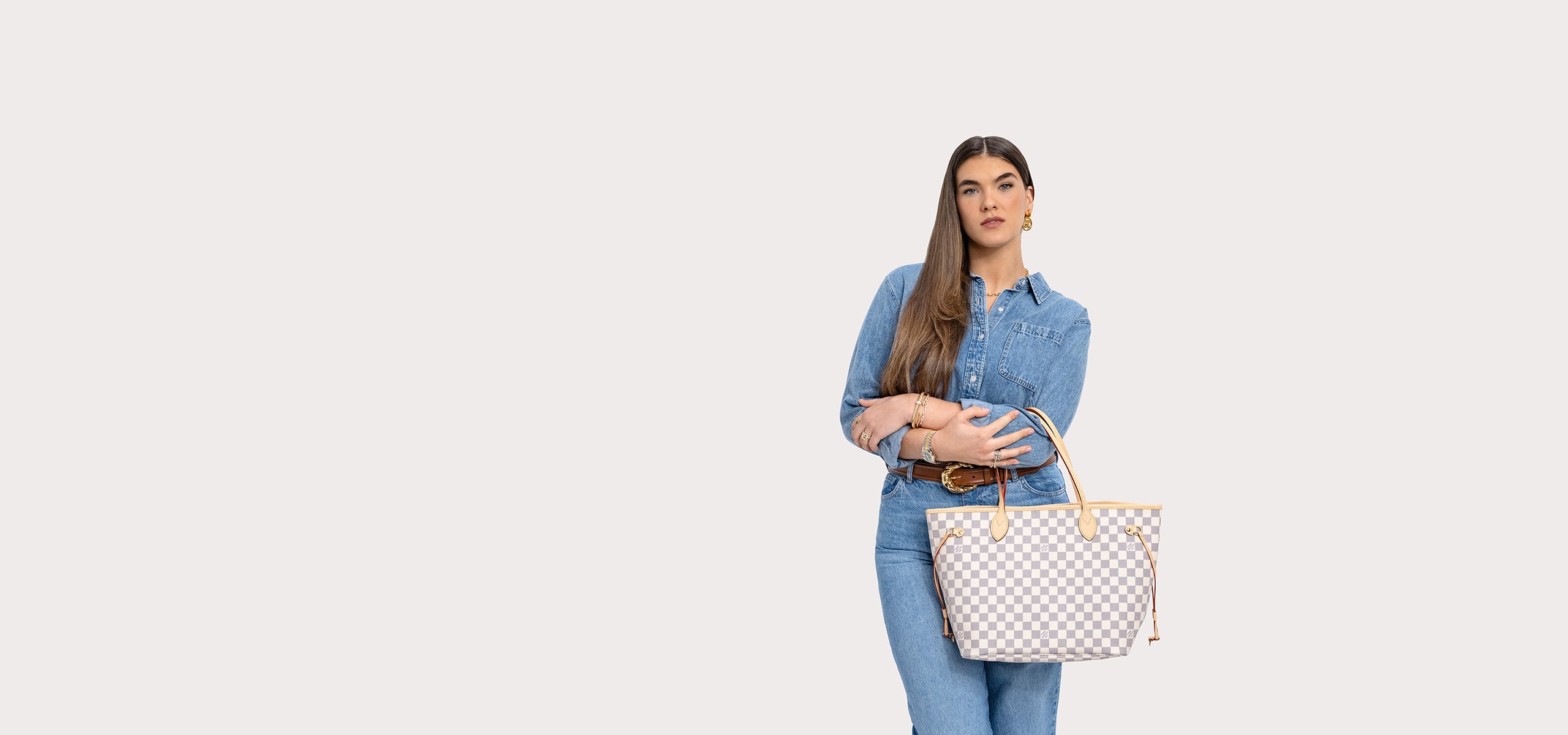 a woman in a denim button down and pants holding a Louis Vuitton Damier Azur Neverfull