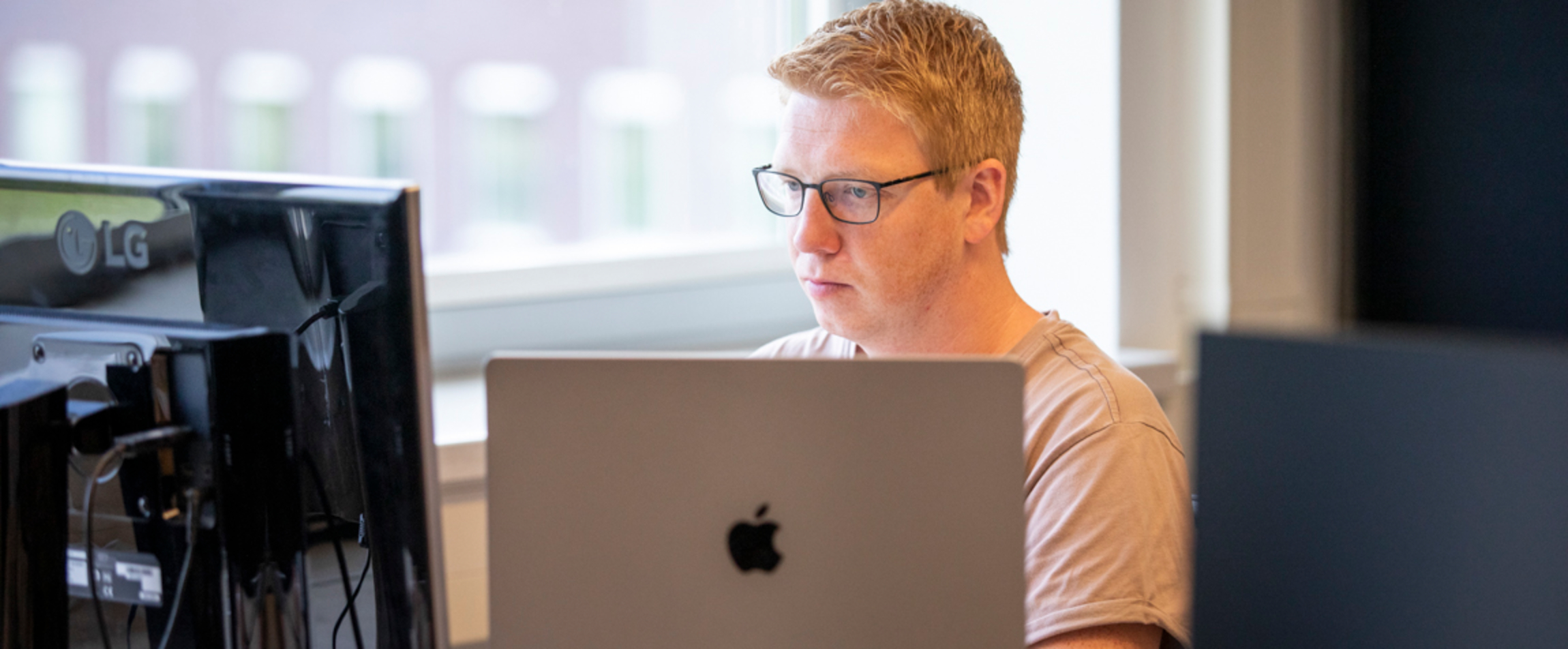 UX designer Stef is druk aan het werk naast het raam.