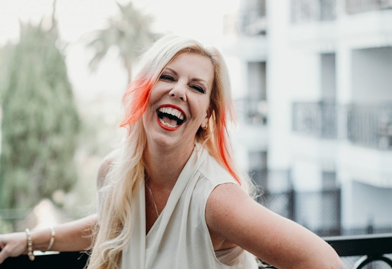 Portrait of Janelle Hoyland laughing on a balcony