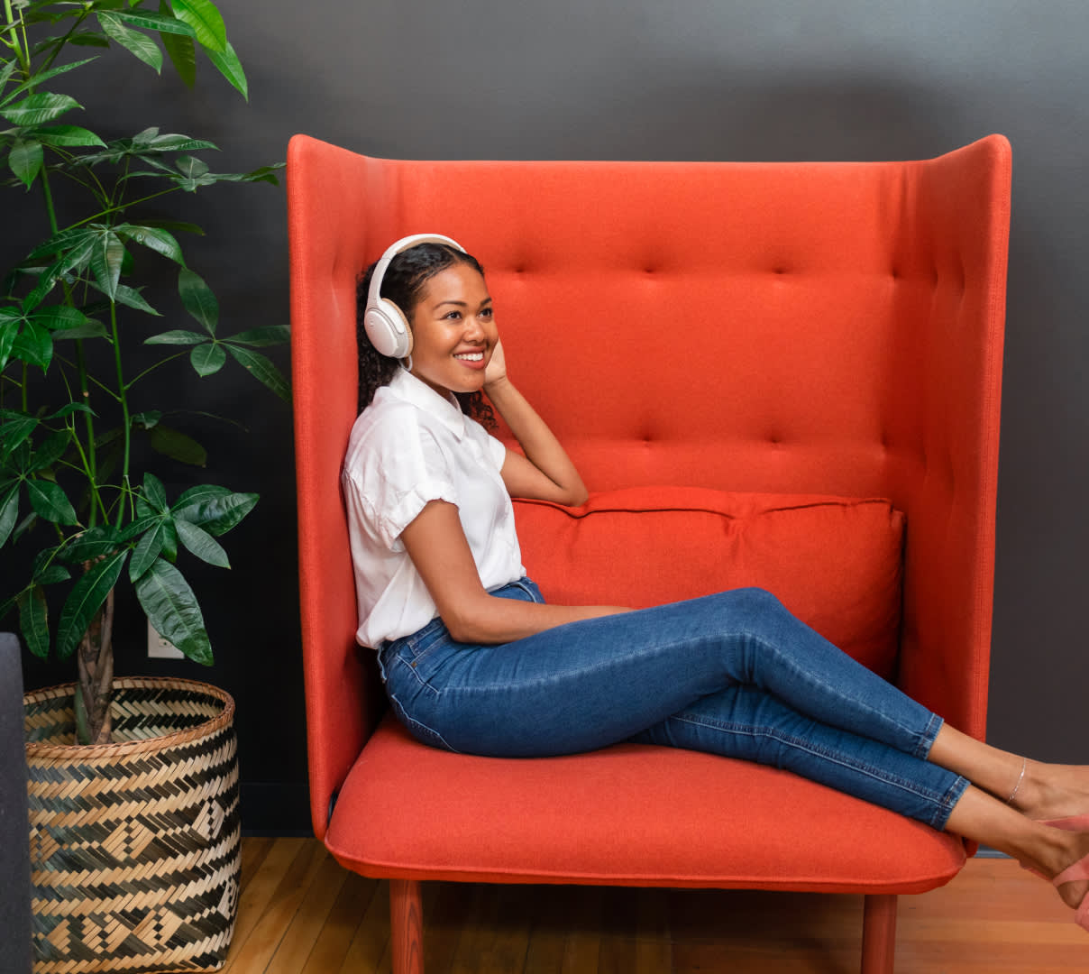 Women wearing headphones and sitting on an armchair