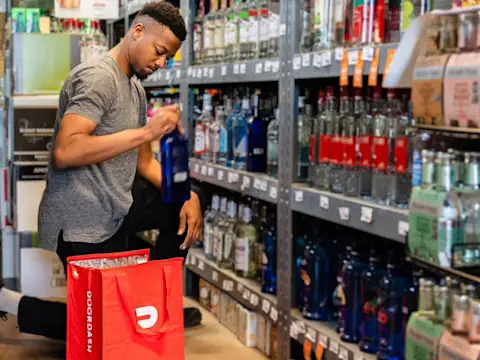 A store clerk packs a bottle into a DoorDash cooler bag.