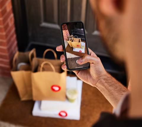 Dx Blog  - How Does Pizza Delivery Work on DoorDash? - Dasher taking picture of delivery with phone