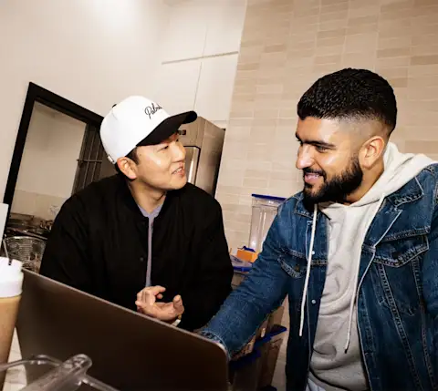 Mx Blog  - Comparing In-House and Third-Party Delivery Services for Restaurants - Merchants looking at laptop