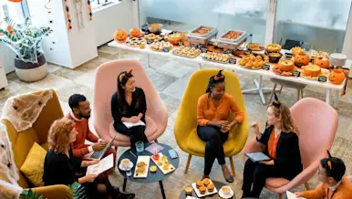 Coworkers sitting down an lunch in a Halloween themed potluck