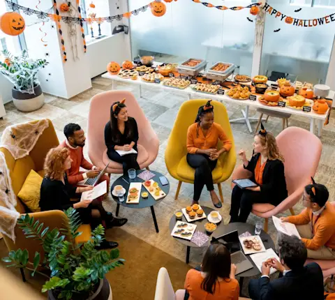 Coworkers sitting down an lunch in a Halloween themed potluck