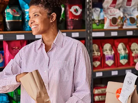 Woman behind counter of a pet store with DoorDash bags on counter