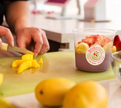 Server chopping mangos for smoothie bowl at Bon Bon Berry