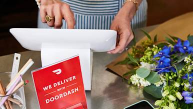 Small business counter with POS and phone with DoorDash coupons and flowers